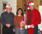 Santas David Isenman and Reinhart Reithmeier award a door prize to Liliana Attisano